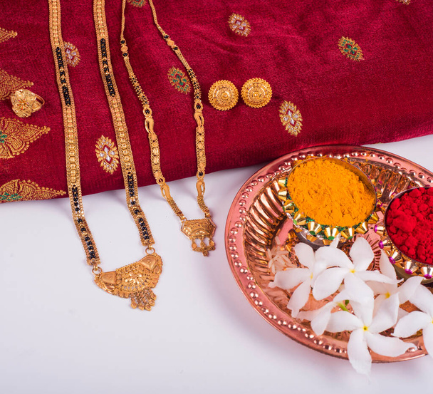 Mangalsutra or Golden Necklace to wear by a married hindu women, arranged with traditional saree with haldi, kumkum and flowers on plate - Fotó, kép