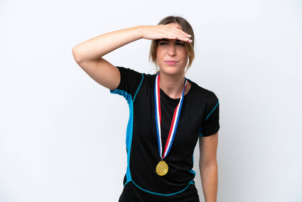 Mujer joven caucásica con medallas aisladas sobre fondo blanco mirando lejos con la mano para mirar algo - Foto, Imagen
