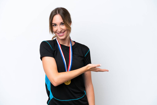 Young caucasian woman with medals isolated on white background presenting an idea while looking smiling towards - Foto, immagini