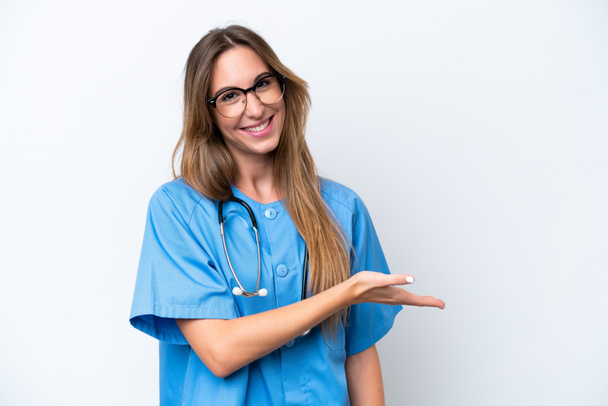 Młoda chirurg lekarz kobieta odizolowana na niebieskim tle prezentując pomysł, patrząc uśmiechnięty do - Zdjęcie, obraz