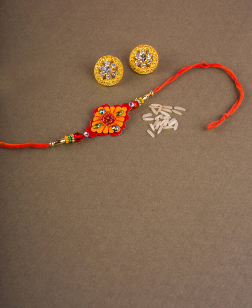 Raakhi with rice grains,kumkum and beautiful earrings gift for the sister given by brother on the occasion of Raksha Bandhan.A traditional Indian wrist band which is festival for brothers and sisters - Fotó, kép