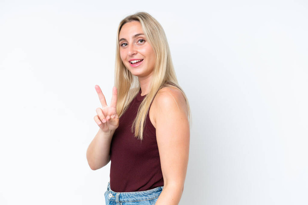 Young caucasian woman isolated on white background smiling and showing victory sign - Foto, Imagen