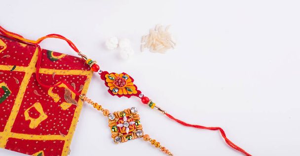 Indian traditional Festival Rakhi with rice grains, kumkum and gift envelope on background with an elegant Rakhi. A traditional Indian wrist band which is festival for brothers and sisters. - Foto, Imagen