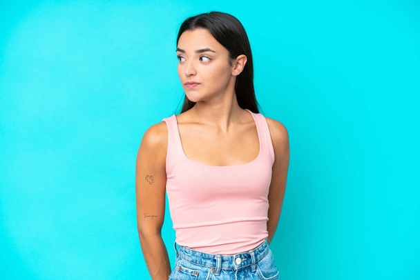 Young caucasian woman isolated on blue background looking to the side - Photo, Image