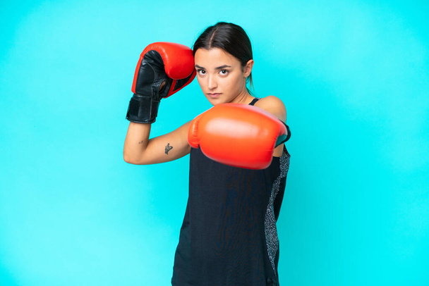 Giovane donna caucasica isolata su sfondo blu con guanti da boxe - Foto, immagini