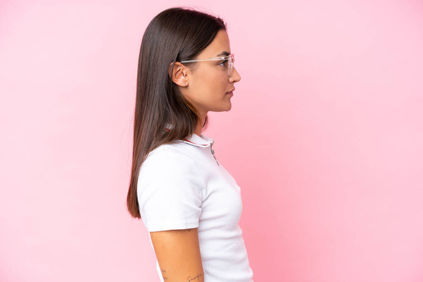 Молодая белая женщина, изолированная на розовом фоне в очках - Фото, изображение