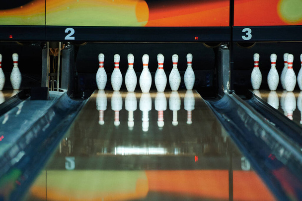 White bowling pins reflecting in bowling alley lane - Fotó, kép