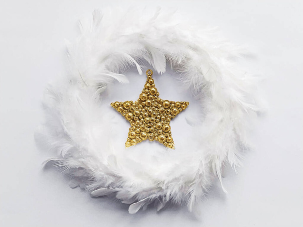White fuzzy wreath made from feathers with big golden star inside. Interior Christmas decoration on minimal style - Fotoğraf, Görsel
