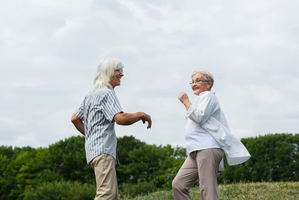 happy retired couple in glasses dancing and smiling outside  - Foto, Imagem