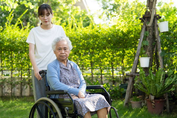 Pečovatel pomoc a péče Asijské starší nebo starší žena pacient sedí na invalidním vozíku v parku, zdravé silné lékařské koncepce. - Fotografie, Obrázek