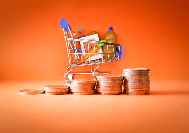 Inflation, growth of Groceries sales, growth of market basket or consumer price index concept. Coins in the form of an ascending graph with Shopping cart with groceries - Photo, image
