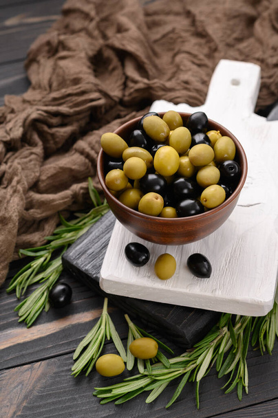 Black and green olives on a dark wooden rustic background. - Zdjęcie, obraz