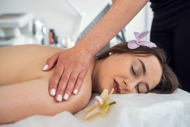  female client enjoying in relaxing her back massage in spa salon, relaxation therapy - Photo, Image