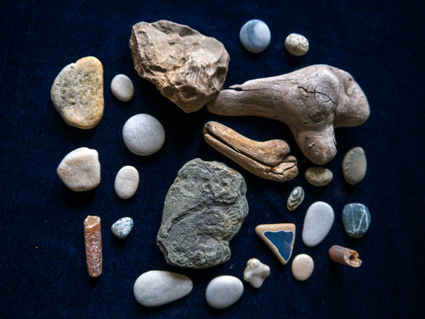 A personal collection of stones,  some bought,some found on beaches,market stalls and mountains on my travels.Collection of stones and driftwood some with fossil remains embedded in them - Photo, image