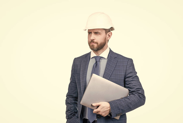 sebevědomý podnikatel muž v obleku a přilbě držet počítač izolovaný na bílém, architekt. - Fotografie, Obrázek