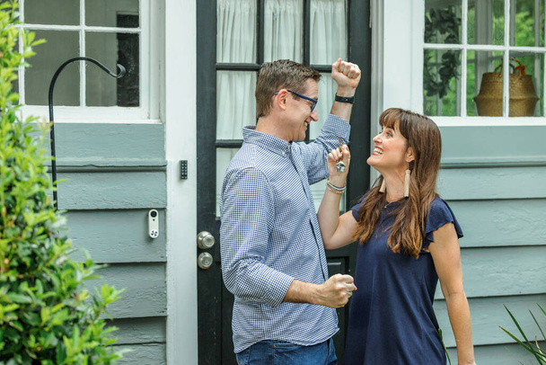A woman holding up the house key to her husband for their new home in this fast paced real estate market. - Zdjęcie, obraz
