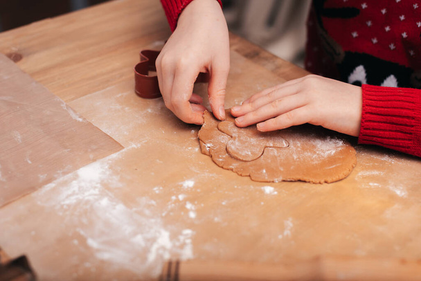 Baking holiday cookies. Child decorates Christmas cookies with icing. Seasonal Christmas lifestyle at home with children. Santa helper. - 写真・画像