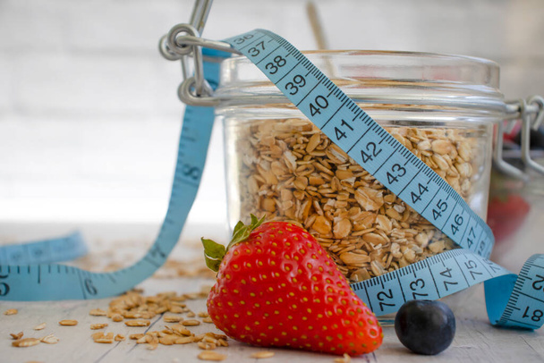 Oatmeal, strawberry, measuring tape on wooden background - 写真・画像