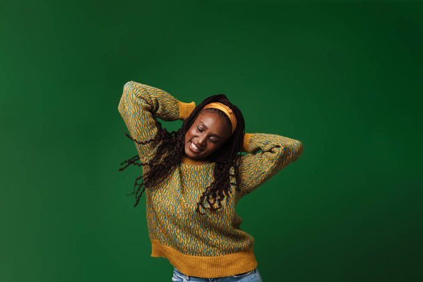 Black young woman with pigtails smiling and dancing isolated over green wall - Fotografie, Obrázek