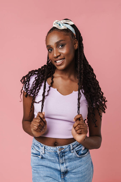 Black young woman with pigtails smiling and looking at camera isolated over pink wall - 写真・画像