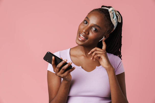 Black young woman listening music earphones and cellphone isolated over pink wall - Φωτογραφία, εικόνα