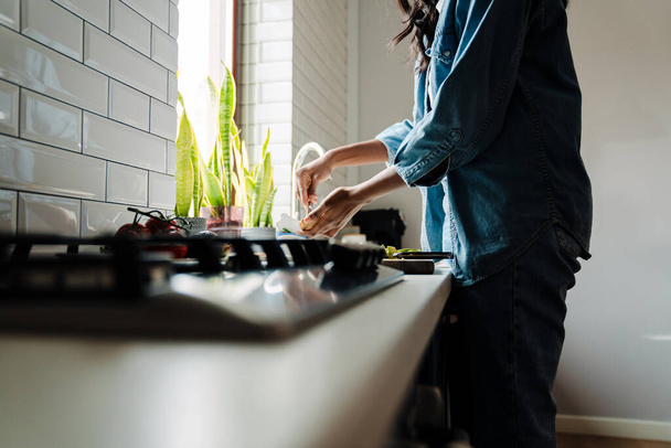 Black young woman wearing denim clothes cooking in kitchen at home - Photo, image