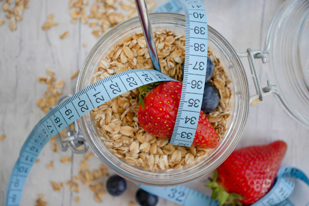 Oatmeal, strawberry, measuring tape on wooden background - 写真・画像