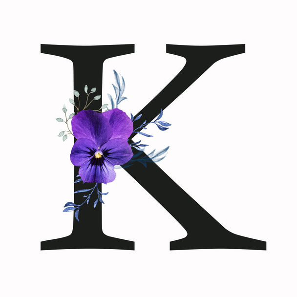 Capital letter K decorated with pansy flower and blue green leaves. Letter of the English alphabet with floral decoration. Floral letter. - Fotografie, Obrázek