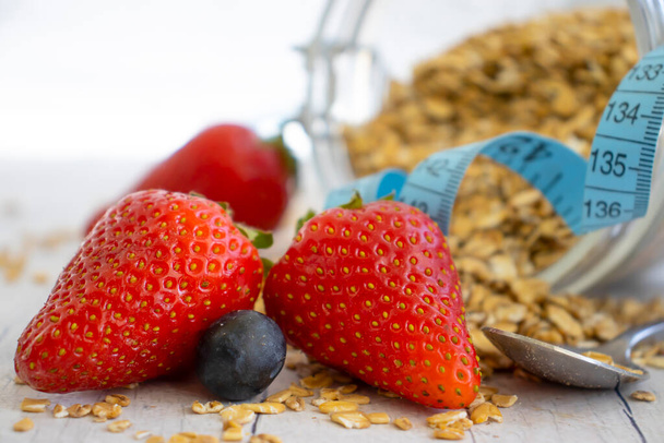 Oatmeal, strawberry, measuring tape on wooden background - Photo, image