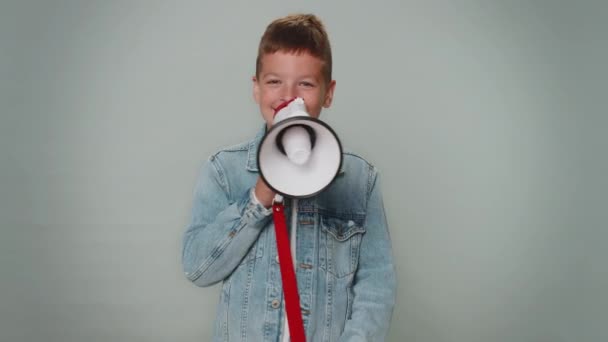Smiling happy toddler boy talking with megaphone, proclaiming news, loudly announcing sale advertisement, warning using loudspeaker to shout speech. Young teenager children. Child on gray background - Footage, Video
