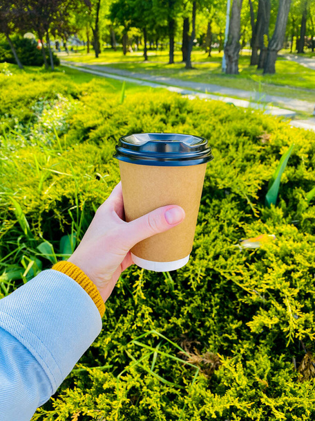 hand holding a paper cup of coffee on a green background - Photo, image