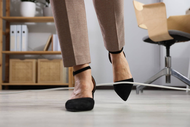 Woman tripping over cord in office, closeup - Foto, imagen