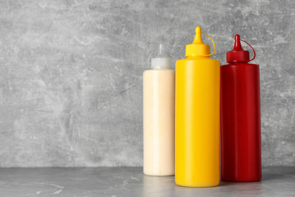 Bottles of mustard, ketchup and mayonnaise on light grey table. Space for text - Fotografie, Obrázek