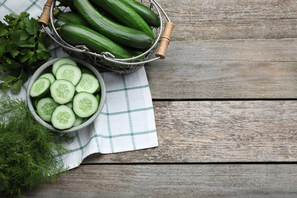 Fresh ripe cucumbers and greens on wooden table, flat lay. Space for text - Zdjęcie, obraz