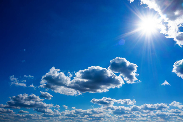 Μπλε ουρανός με λευκά σύννεφα και λαμπερό ήλιο. Αφηρημένο φυσικό υπόβαθρο. - Φωτογραφία, εικόνα