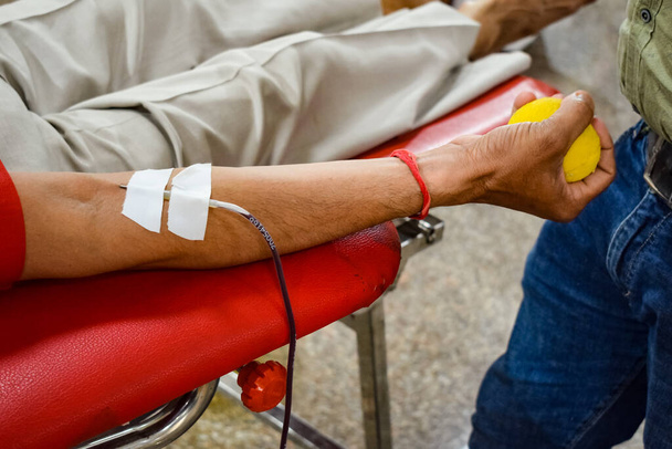 Donante de sangre en el campamento de donación de sangre celebrado con una pelota hinchable sosteniendo en la mano en el Templo Balaji, Vivek Vihar, Delhi, India, Imagen para el Día Mundial del Donante de Sangre el 14 de junio de cada año, Campamento de Donación de Sangre - Foto, Imagen