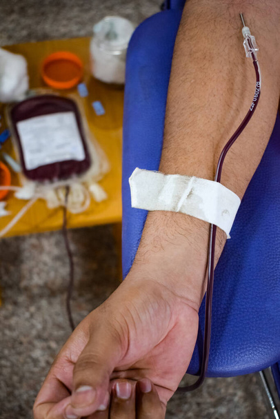 Donante de sangre en el campamento de donación de sangre celebrado con una pelota hinchable sosteniendo en la mano en el Templo Balaji, Vivek Vihar, Delhi, India, Imagen para el Día Mundial del Donante de Sangre el 14 de junio de cada año, Campamento de Donación de Sangre - Foto, imagen