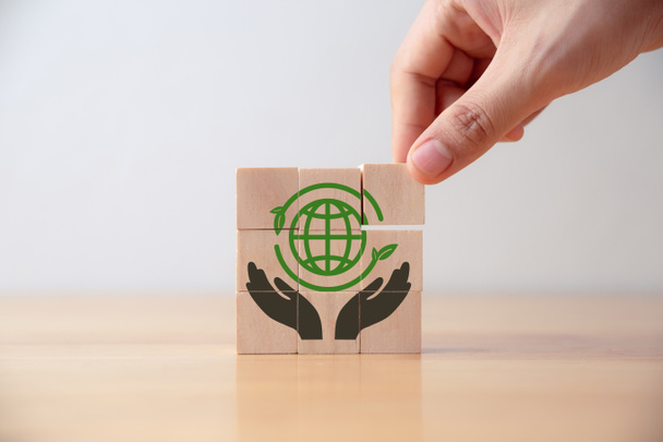 Рука молодого человека положил деревянный куб с иконой зеленого мира на стол, спасти мир, устойчивая концепция окружающей среды. - Фото, изображение