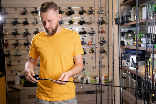 Uomo shopper scegliendo canna da pesca nel negozio di pesca, copiare lo spazio - Foto, immagini
