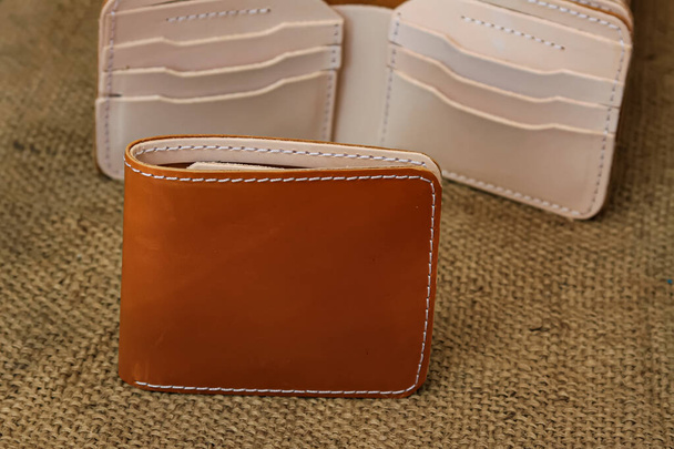 Men's brown leather wallet. With a touch of a netted background or texture on the table. - Foto, Imagen