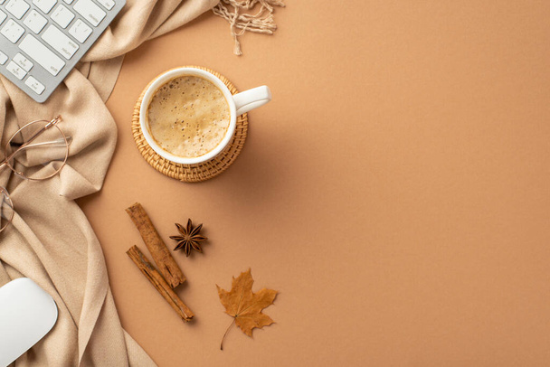 Business concept. Top view photo of cup of frothy drinking rattan serving mat computer mouse keyboard glasses yellow maple leaf cinnamon sticks anise scarf on isolated beige background with copyspace - Foto, Imagen