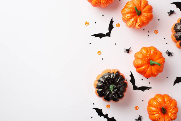 Halloween party decor concept. Top view photo of small pumpkins bat silhouettes spiders and confetti on isolated white background with empty space - Fotografie, Obrázek