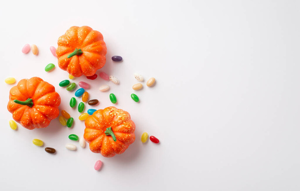 Halloween concept. Top view photo of orange pumpkins and candies on isolated white background with copyspace - Foto, imagen