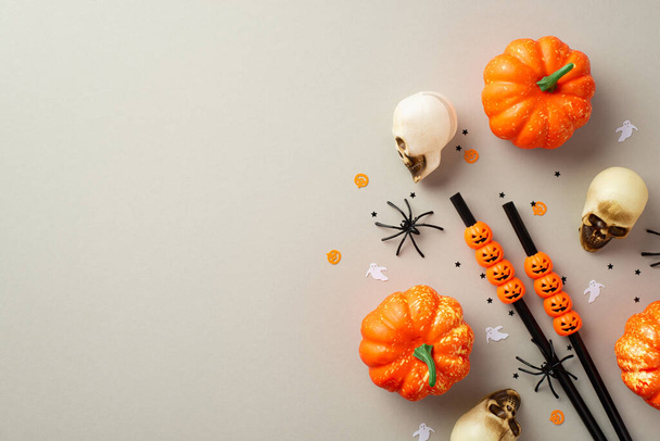 Концепция Хэллоуина. Фото черепа тыквы пауков соломинки и конфетти на изолированном сером фоне с копирайтом - Фото, изображение