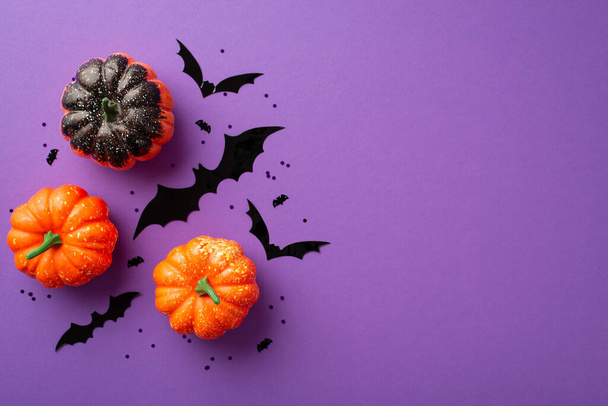 Halloween concept. Top view photo of pumpkins bat silhouettes and black confetti on isolated violet background - Foto, afbeelding