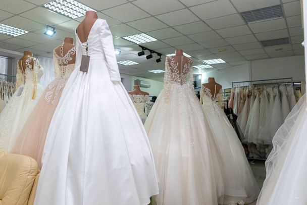 Several wedding dresses on mannequins in a wedding salon. Rear view. - 写真・画像