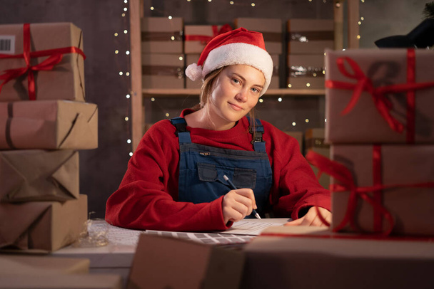 Malý podnikatel majitel v Santa klobouku při objednávce on-line v domácí kanceláři v noci, vánoční doručení strat nahoru. MSP, elektronický obchod, koncepce lodní dopravy - Fotografie, Obrázek