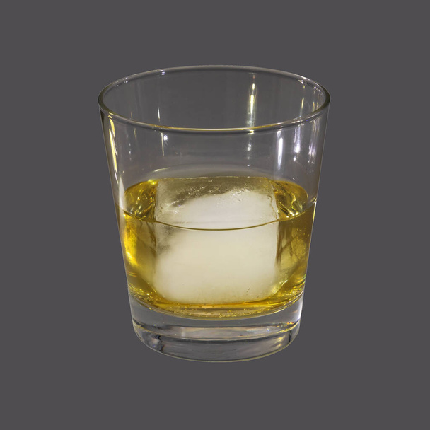 Studio photograph of a glass with an ice cube on grey background - Foto, afbeelding