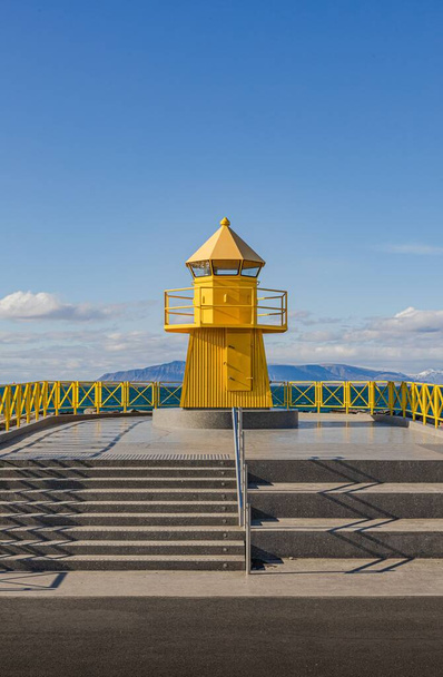A vertical shot of the historic yellow Hofoi lighthouse on the rocky shore of Reykjavik - Foto, Imagem