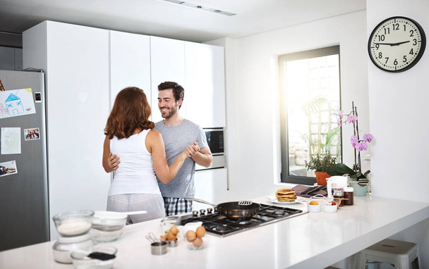 Танцует под ритм дня. молодая пара танцует на кухне во время приготовления завтрака - Фото, изображение